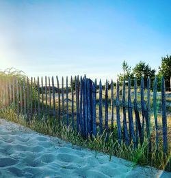 Wooden fence on field against clear blue sky