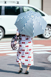 Rear view of woman with umbrella walking on street