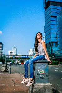 Full length of woman against blue sky in city