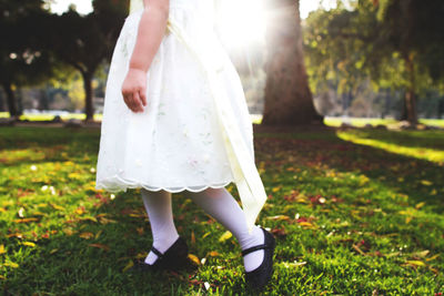 Low section of girl walking on grass in park