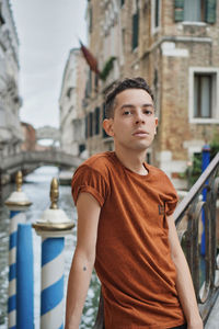 Portrait of teenage boy looking away against buildings in city