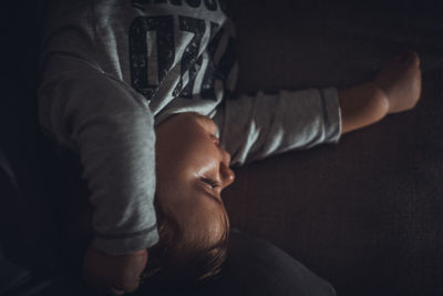 High angle view of cute baby boy lying on sofa at home