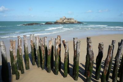 Panoramic view of wooden posts on beach against sky