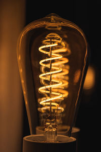 Close-up of illuminated light bulb against black background