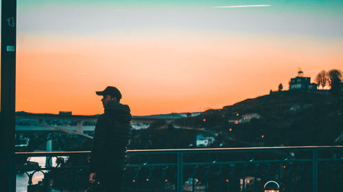 Rear view of man photographing against sky during sunset