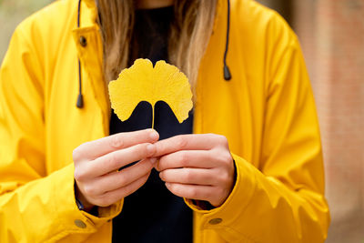 Midsection of woman holding yellow leaf