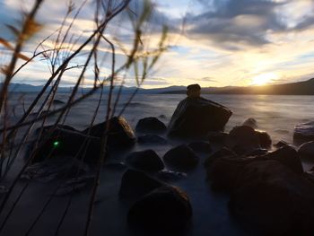 Silhouette rocks on beach against sky during sunset