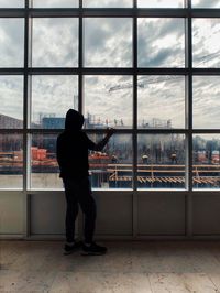 Rear view of man looking through window