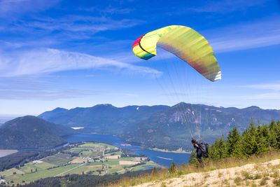 Person paragliding over mountains against sky