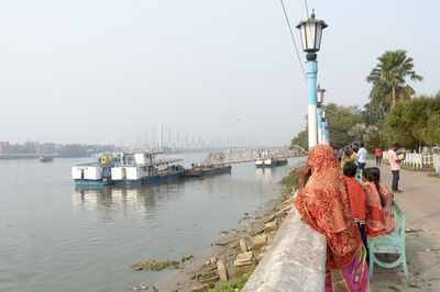 Rear view of people on boat in sea against clear sky