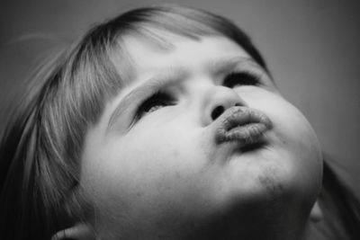 Close-up of cute girl puckering lips while looking up