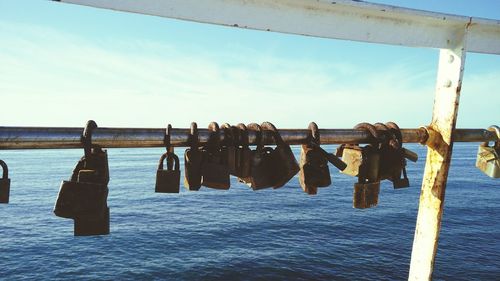 Close-up of padlocks on sea against sky