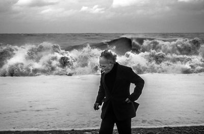 Woman standing at beach against sky