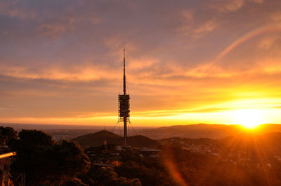 Silhouette communications tower against sky during sunset in barcelona 