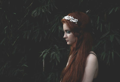 Profile view of young woman wearing tiara against plants