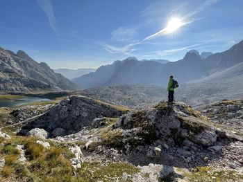 Man standing on rock by mountains against sky