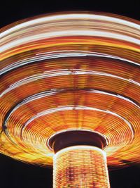 Low angle view of illuminated carousel against sky at night