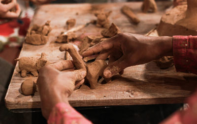 Cropped hands making clay toys on table