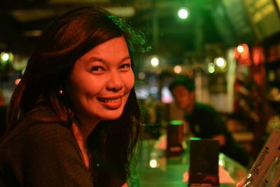 Portrait of young woman in illuminated christmas lights at night