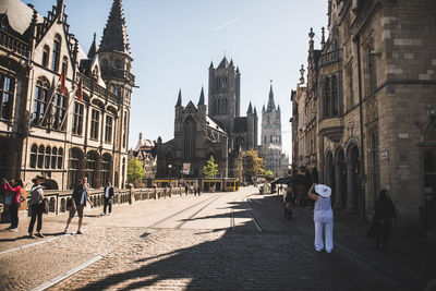 People walking on street amidst buildings in city