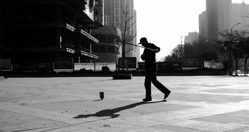 Side view of silhouette man playing on footpath