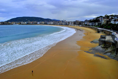 Scenic view of beach by buildings against sky