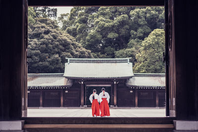 Rear view of woman standing outside temple against building