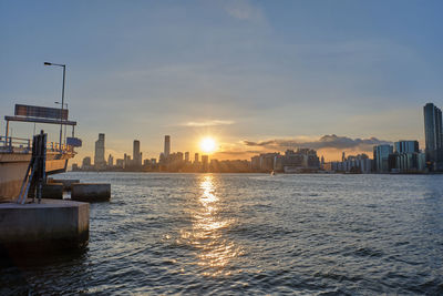 Scenic view of sea by buildings against sky during sunset