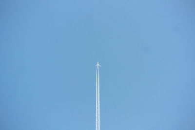 Low angle view of airplane flying against clear blue sky