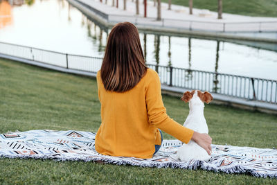 Back view of woman having fun with jack russell dog in park,woman cuddling pet during autumn season