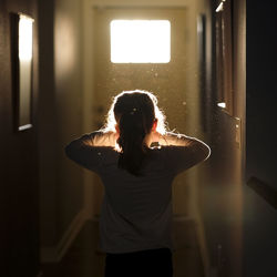 Rear view of girl standing in corridor at home