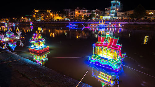 Illuminated buildings by river in city at night soc trang