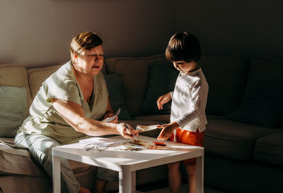 Senior woman counting money americain dollars and euro at home teaching kid financial literacy 