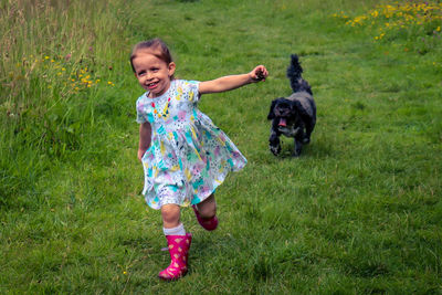 Full length of girl with dog on grass at park