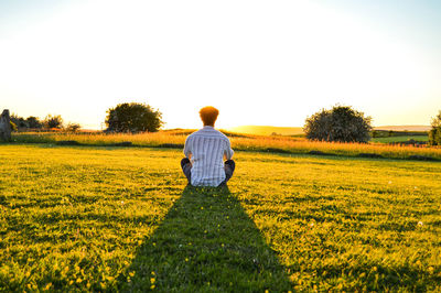 Rear view of man on field against sky