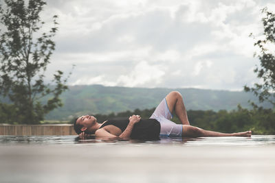 Full length of woman lying in water against sky