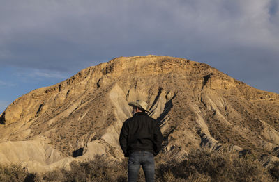 Adult man in cowboy hat standing against mountains in tabernas desert. almeria, spain