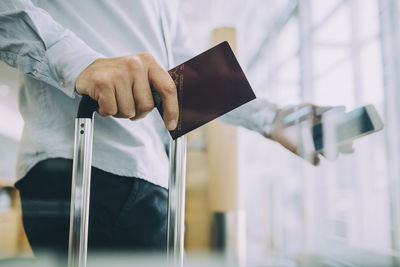 Midsection of businessman holding passport at airport