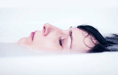 Close-up of woman with eyes closed relaxing in bathtub at home