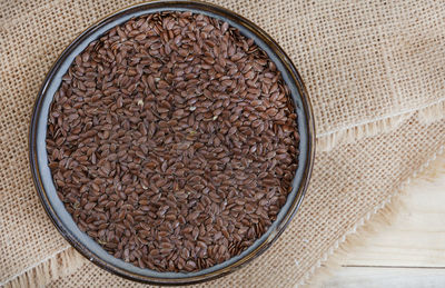 Bowl of whole linseed on hessian and rustic table with copy space