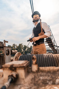 Man standing on motorcycle against sky