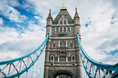Low angle view of tower bridge against cloudy sky