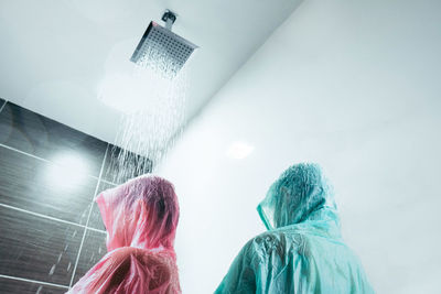  brother and sister wearing raincoat while taking shower in bathroom