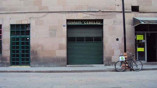 Bicycle parked on footpath against building