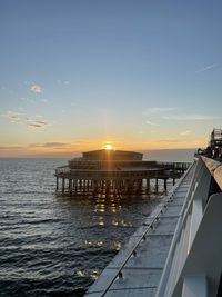 Pier over sea against sky during sunset