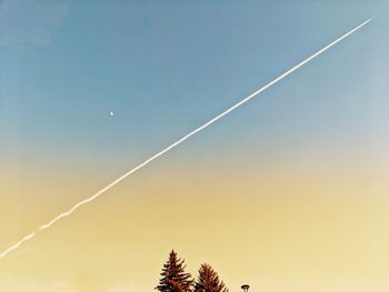 Low angle view of vapor trail against sky during sunset