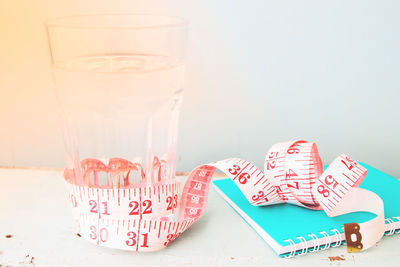 Close-up of drink and tape measure with spiral notebook on table