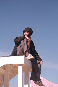 Low angle view of man standing against clear blue sky