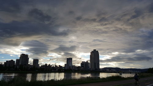 Modern buildings by river against sky in city