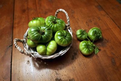 High angle view of fresh green tomatoes in basket and table